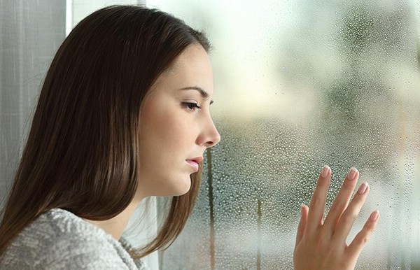 грустная женщина смотрит в окно